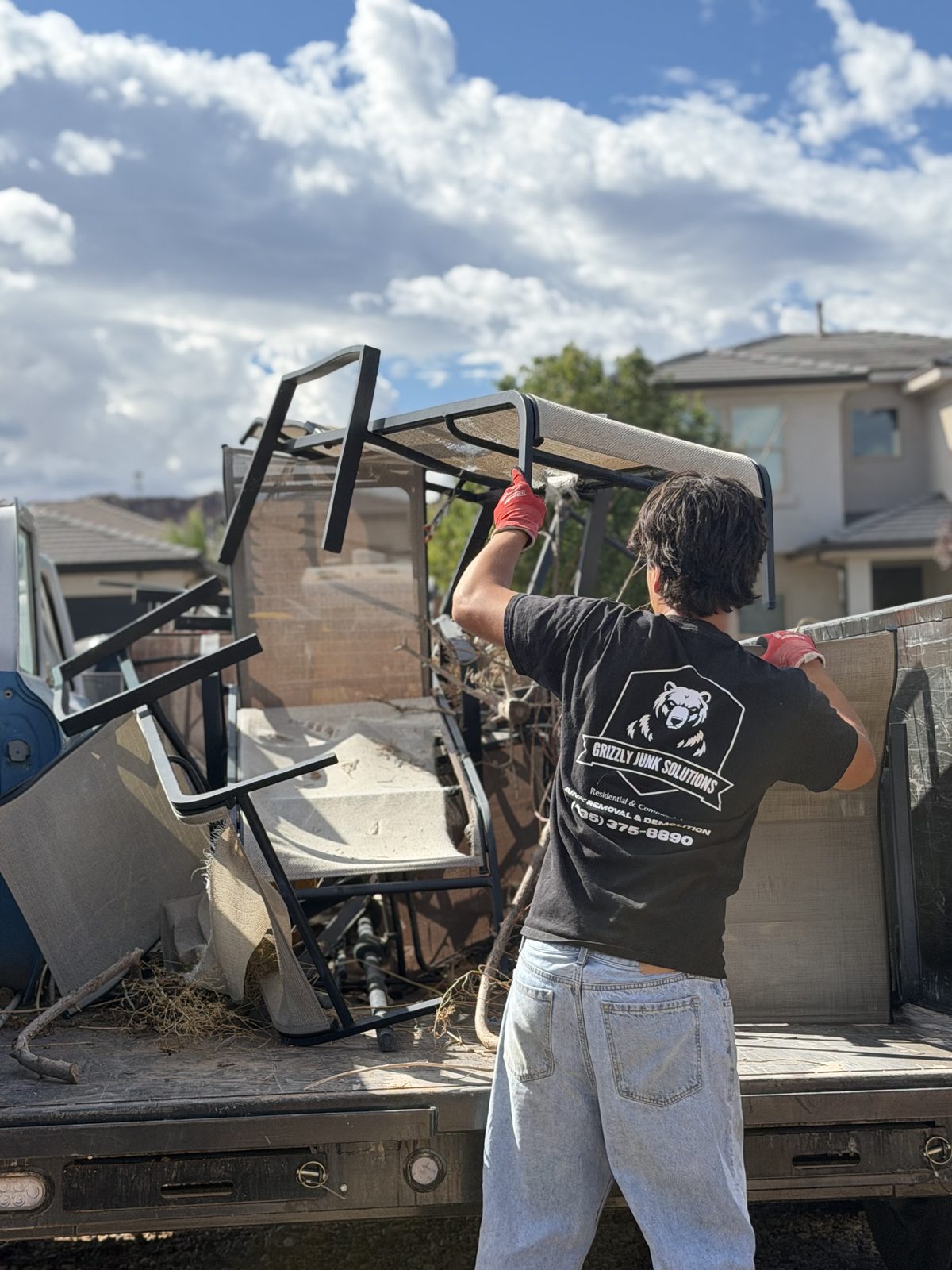 Grizzly Junk Solutions crew member loading patio furniture into the junk removal truck